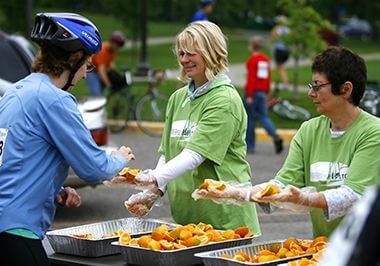 Volunteers Serving Food to Bicyclist