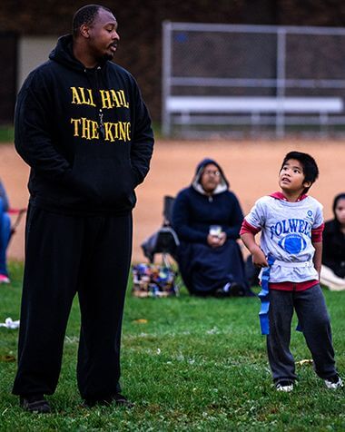 Volunteer Flag Football Coach Talking with Young Player