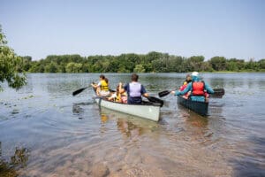 Four people canoeing in two canoes.