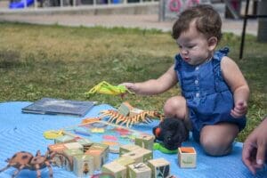 Young child playing with a puzzle and large plastic bugs.