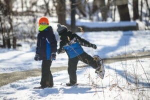 Two kids walking in snowshoes.