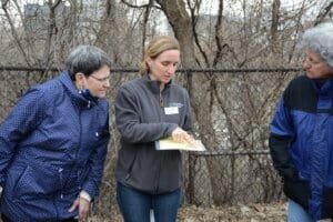 An MPRB naturalist pointing to an example during a naturalist walk with two women.