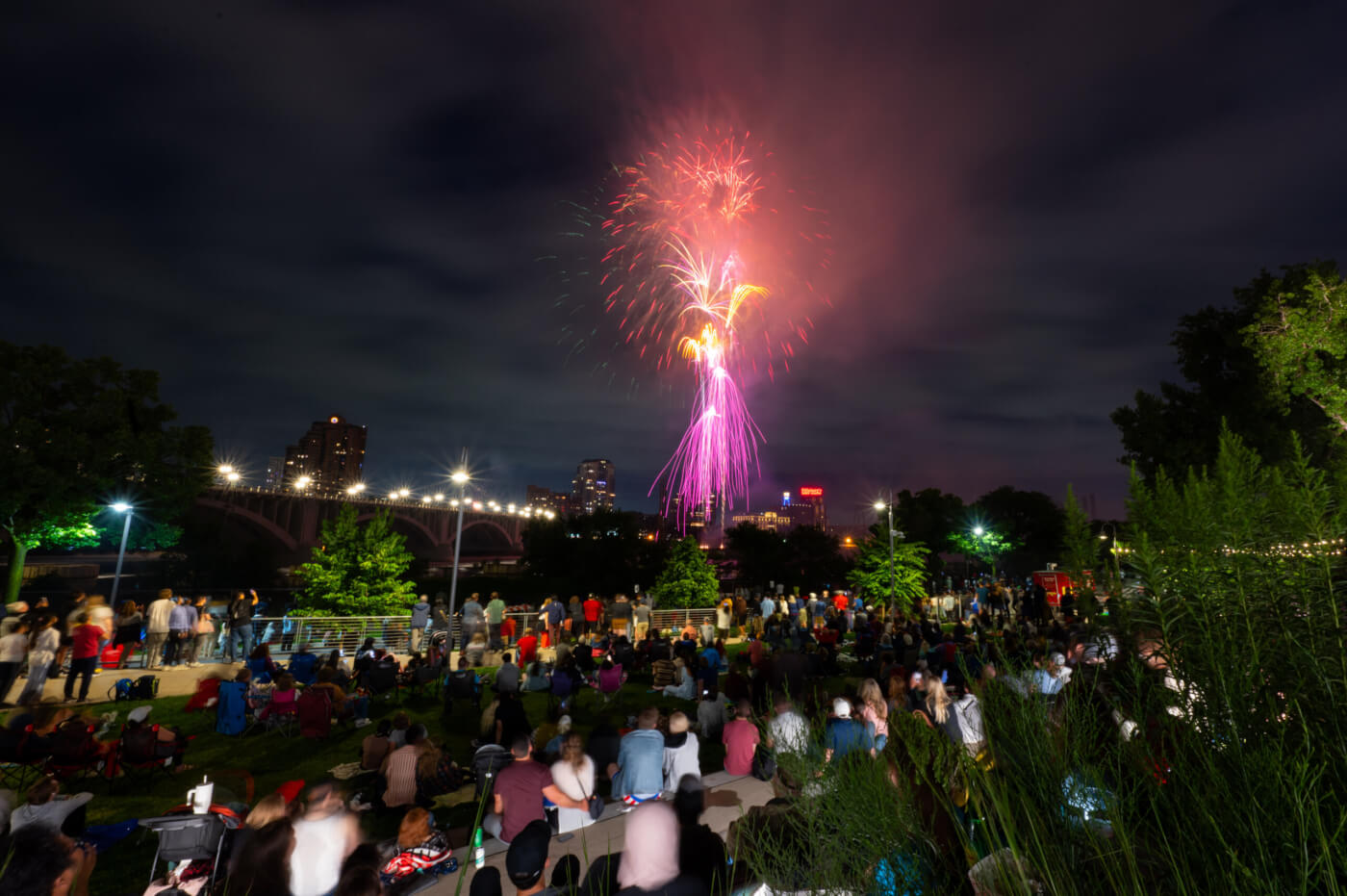People watch pink, red and orange fireworks