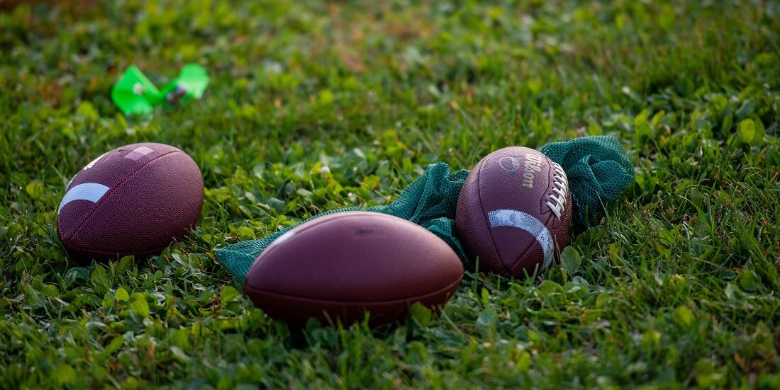 Footballs laying in grass
