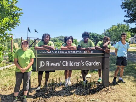 Youth Standing Next to the JD Rivers' Children's Garden Sign